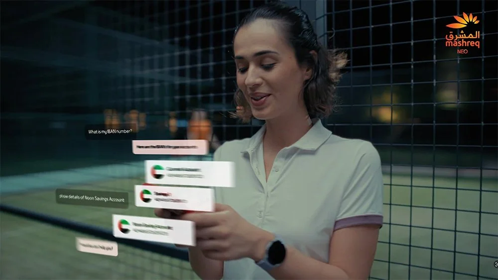 Woman using a transparent virtual interface with banking options on her smartphone at night near a wire fence.