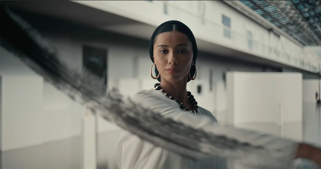 A woman with earrings and a necklace holding a newspaper at an airport or train station.