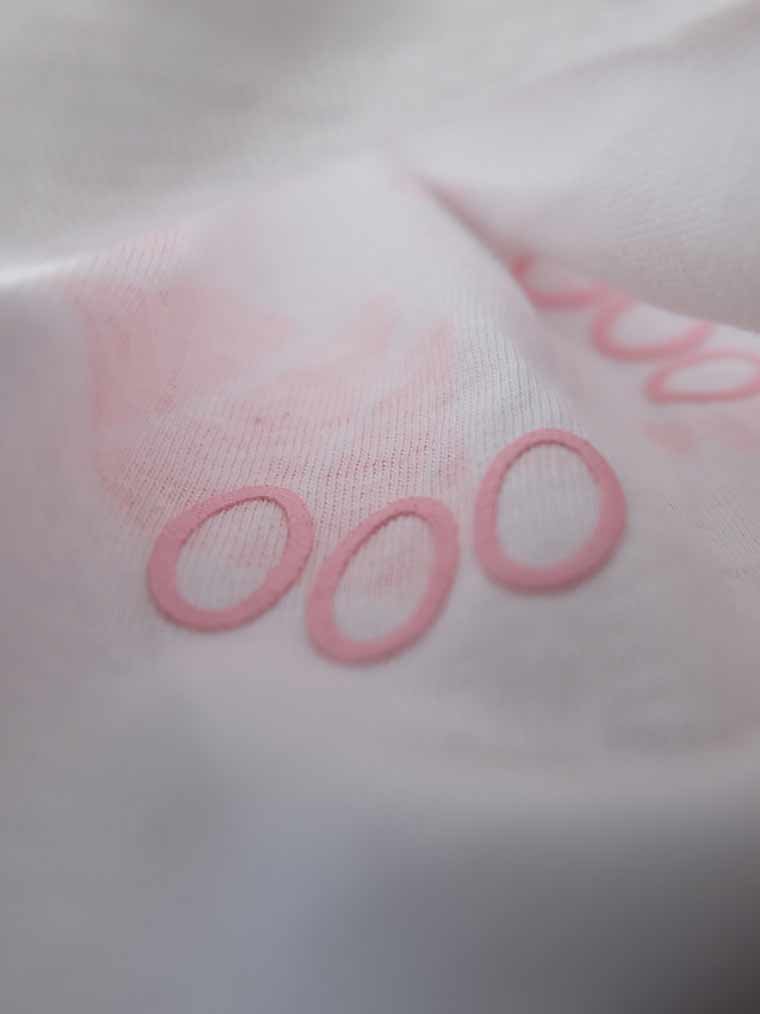 Close-up of a crumpled white fabric with pink embossed lettering.