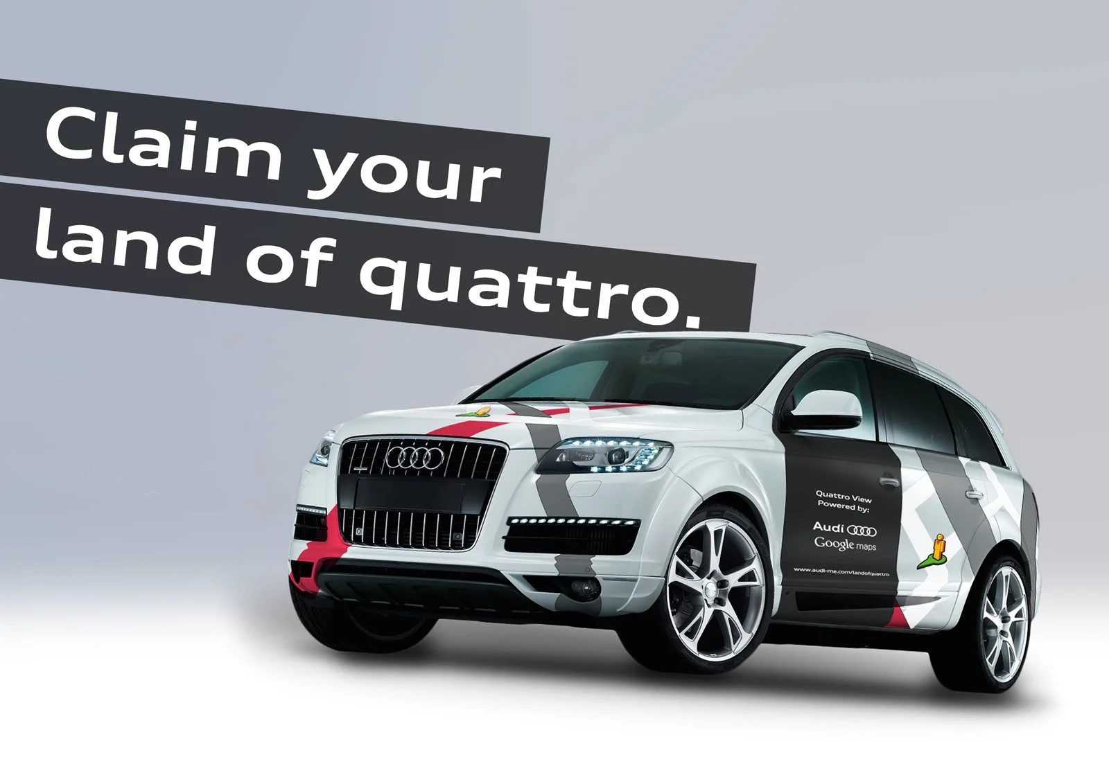 A white Audi Quattro SUV with black, gray, and red racing stripes, and a claim that reads "Claim your land of quattro."