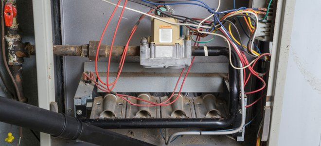 Interior of an electrical or HVAC control panel with wiring, components, and a black insulated pipe.