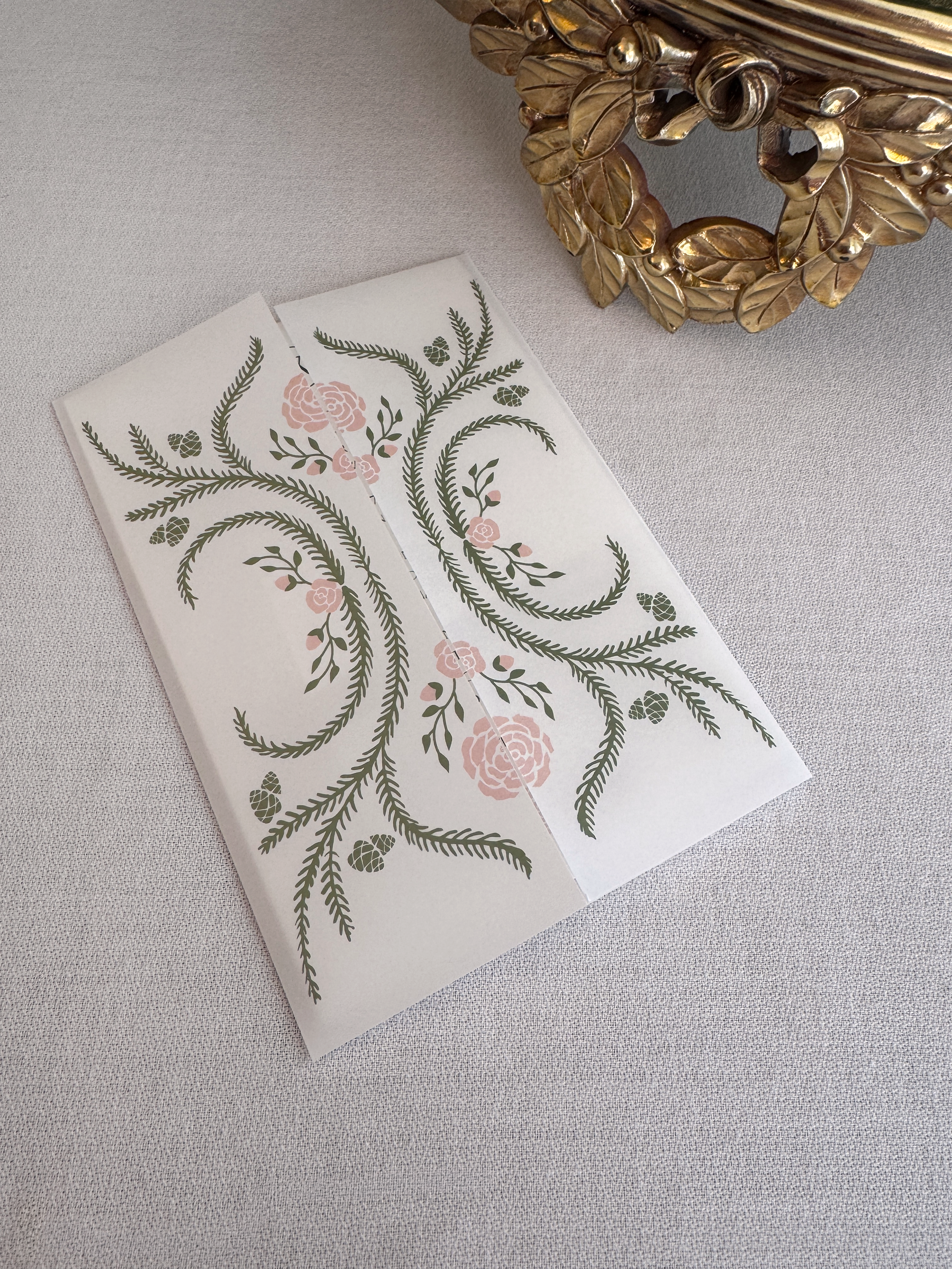 A paper with a floral pattern, featuring pink roses and green leaves, placed on a light textured surface.