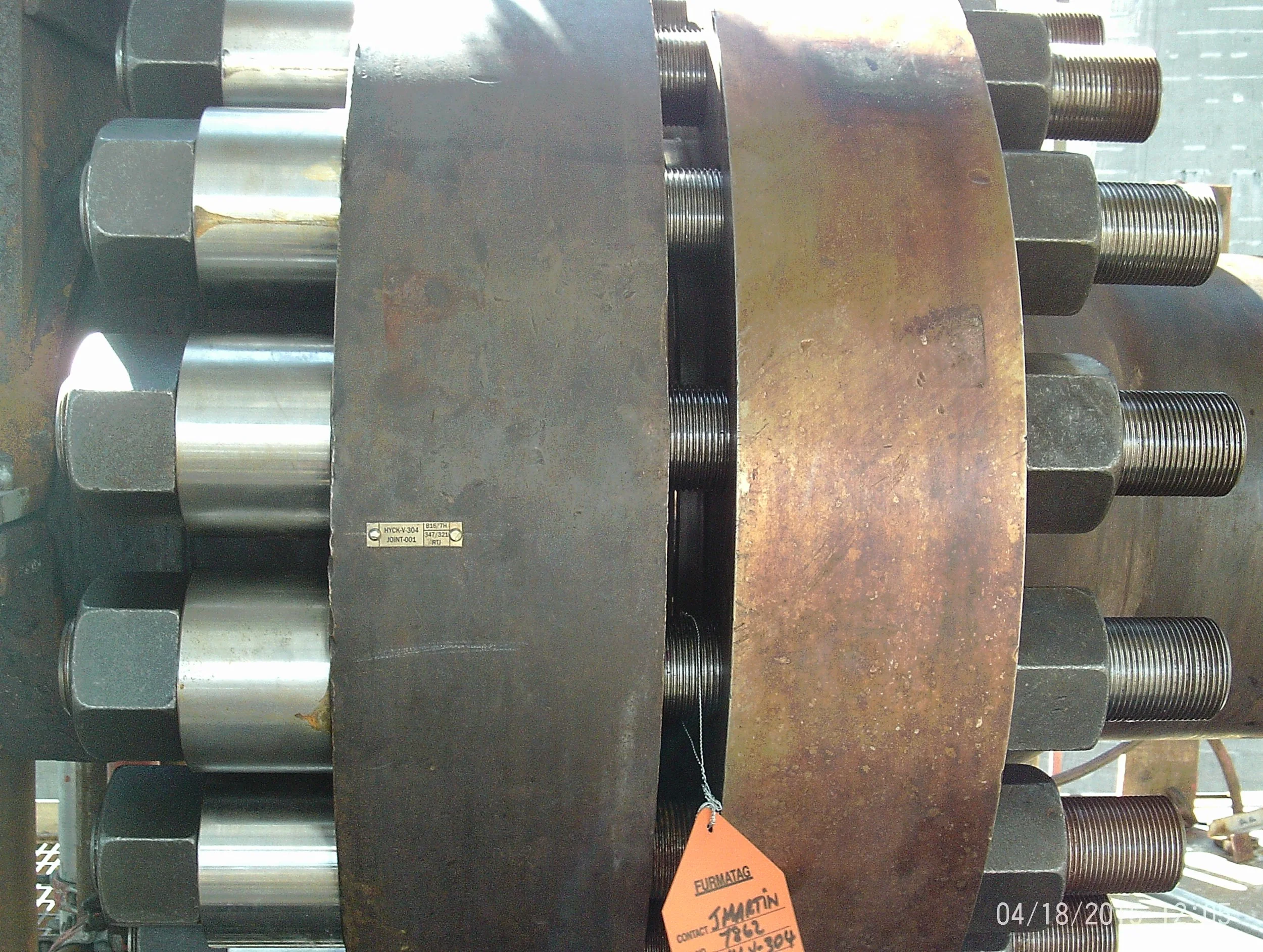 Close-up view of a stack of engine or mechanical parts, including large bolts, metal rings, and a rusty metal plate.
