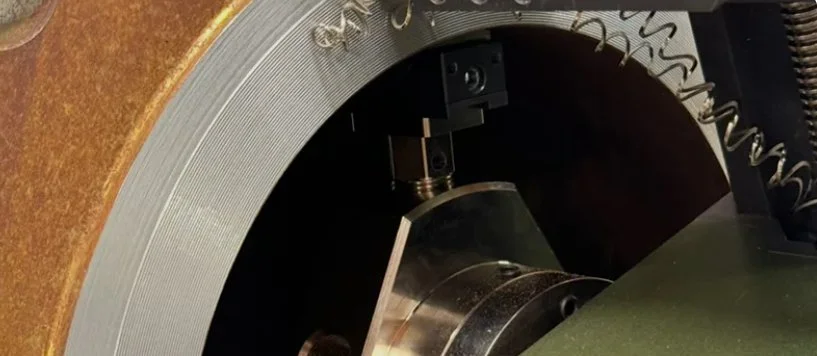 Close-up of a mechanical device with metallic and wooden components, including a coil spring and cylindrical parts.