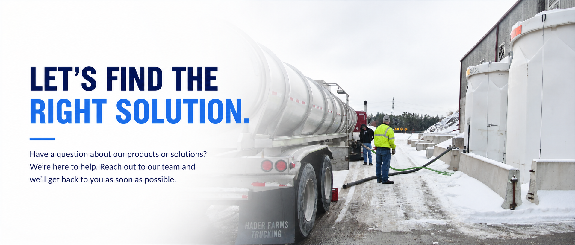 A winter scene at an industrial site shows a large tanker truck, several workers in safety gear, and a snow-covered area, with a building and trees in the background.