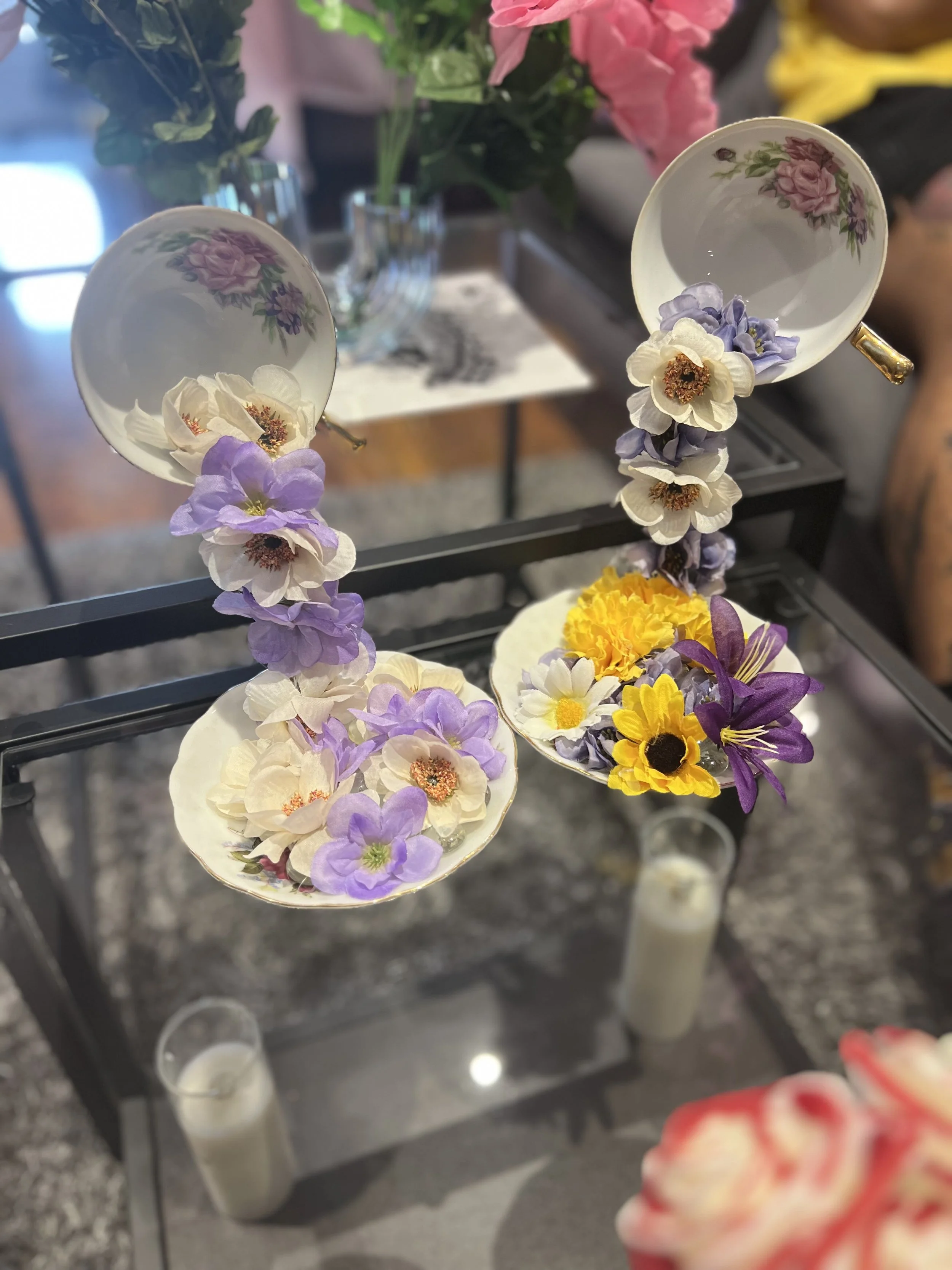 Decorative floral earrings with small, colorful flowers in white and purple, hanging on a black display stand.