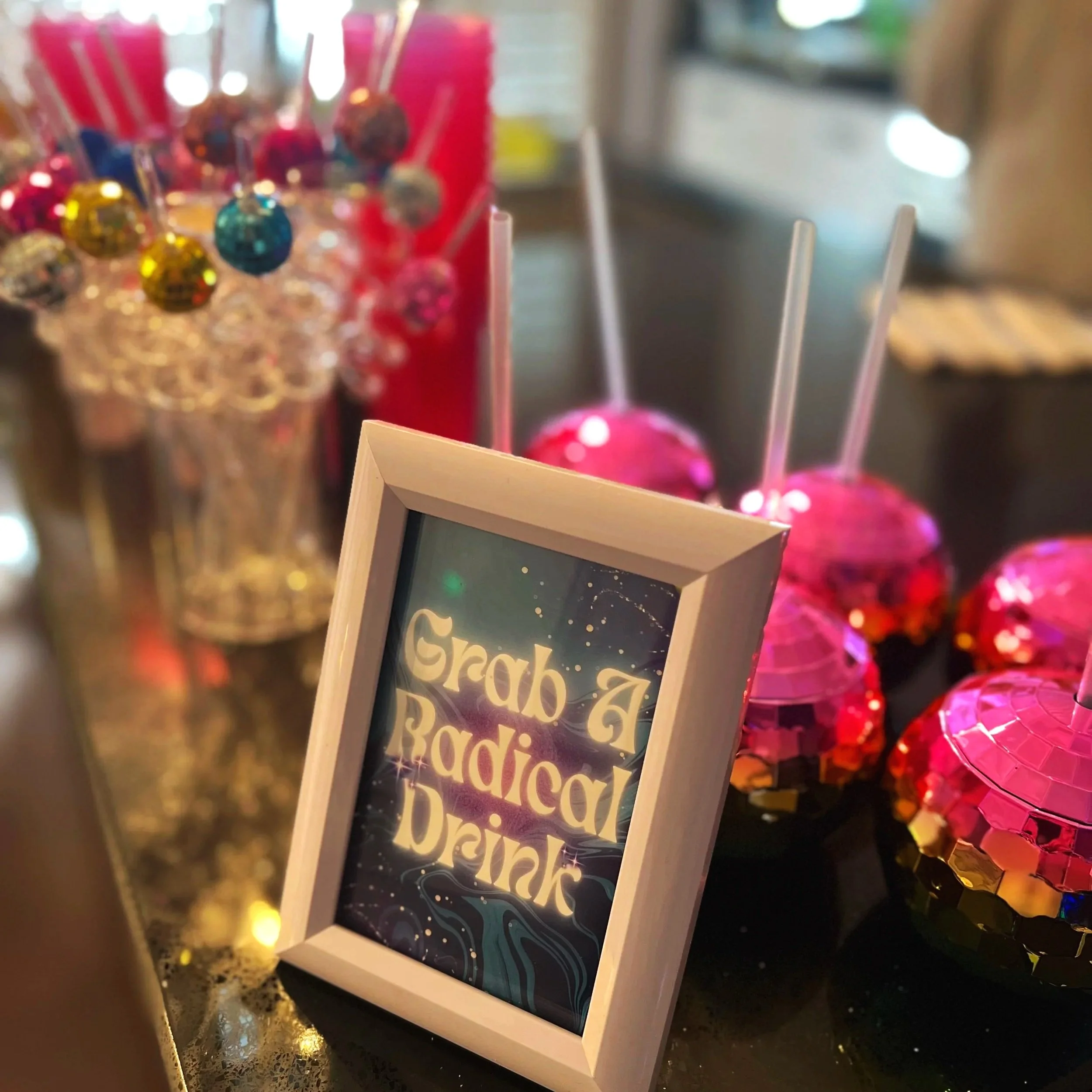 Close-up of a decorative display with colorful ornaments and a small framed sign, possibly at a festive event or market.