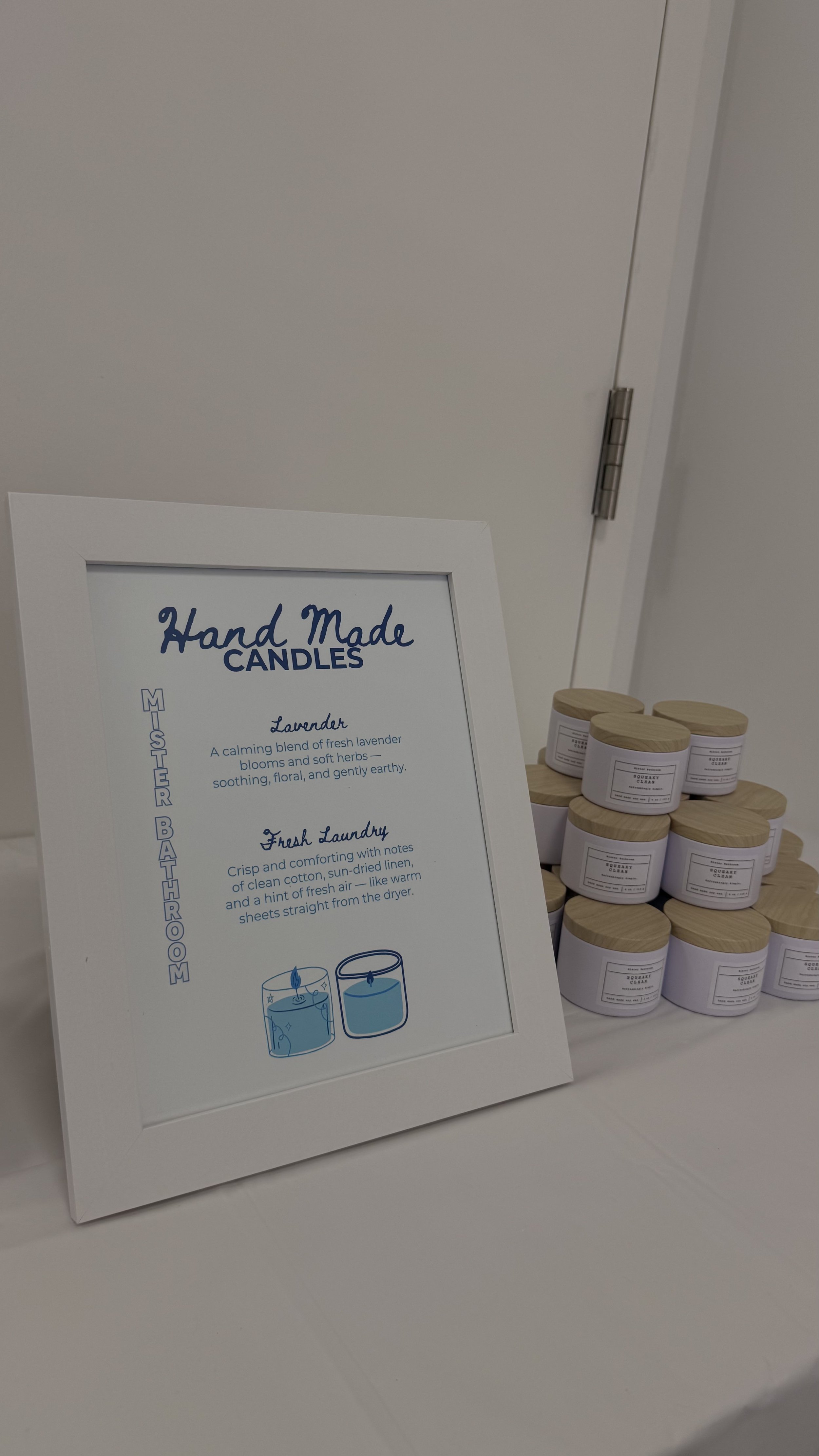 Display of handmade candles with a sign describing their scents and benefits, stacked in a pyramid shape.