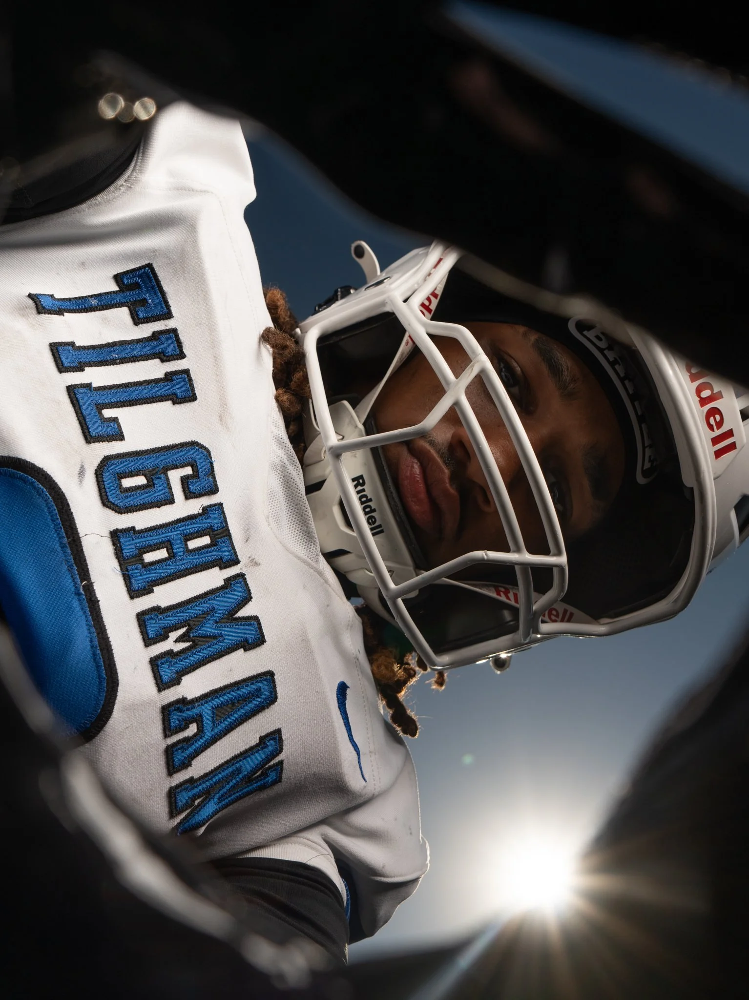 Close-up of a football player in a white jersey with blue lettering and a white helmet.