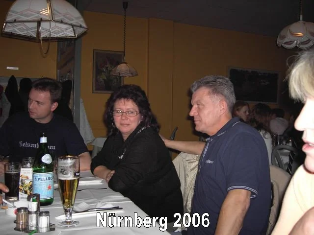 Menschen sitzen an einem Tisch in einem Restaurant, trinken Bier, im Hintergrund sind weitere Gäste und Bilder an der Wand, es ist wahrscheinlich ein Treffen in Nürnberg im Jahr 2006.