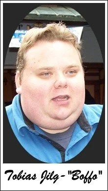 Ein junger Mann mit blonden, kurzen Haaren, trägt ein blaues Hemd und schaut nach rechts.