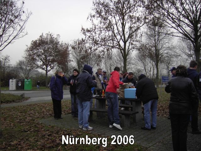 Gruppe von Menschen versammelt sich im Park in Nürnberg 2006, einige trinken, andere sprechen, es ist nebliges Wetter mit herbstlichen Bäumen im Hintergrund.
