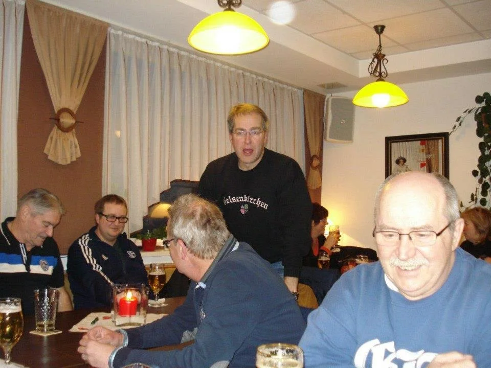 Gruppen von Menschen, die in einem Restaurant oder einer Bar zusammen sitzen, während einer in der Mitte spricht.