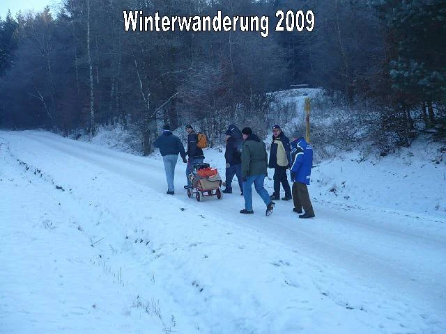 Eine Gruppe von Menschen wandert im Schnee bei einer Winterwanderung im Jahr 2009 in einer winterlichen Landschaft.