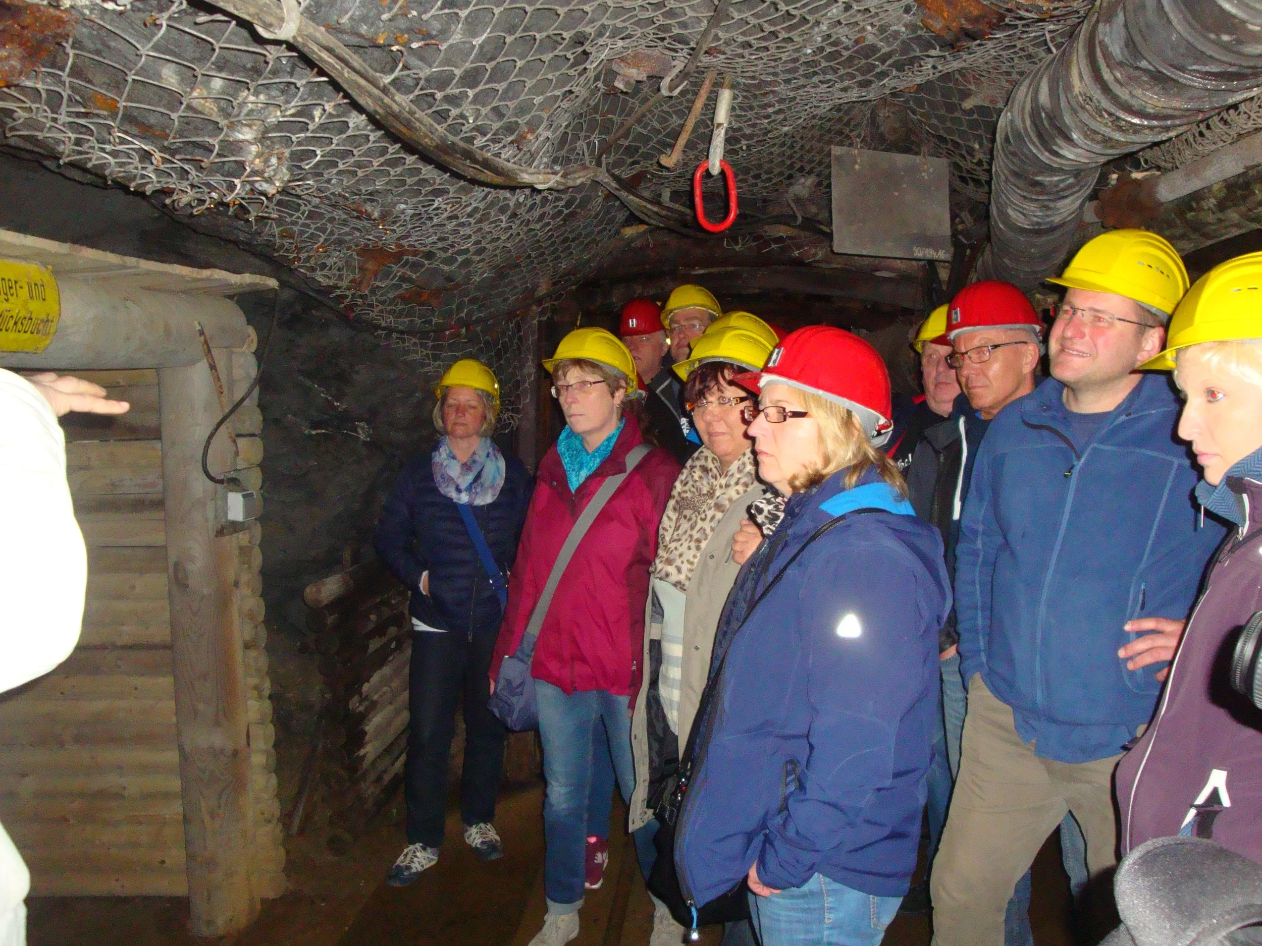 Eine Gruppe von Menschen mit Schutzhelmen, die eine Führung in einem Tunnel oder Bergwerk machen.