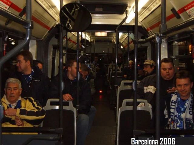 Menschen sitzen in einem Bus, einige tragen Trikots und Schals, bei Nacht, in Barcelona im Jahr 2006.