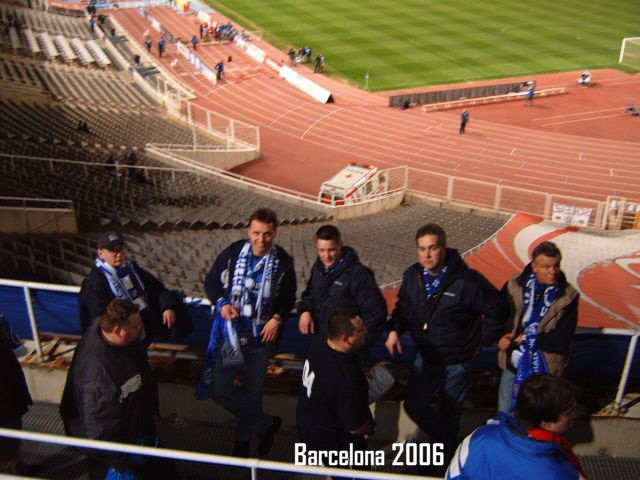 Eine Gruppe von Personen, vermutlich Fans, steht in einem leeren Stadion mit Laufbahn, im Jahr 2006 in Barcelona.
