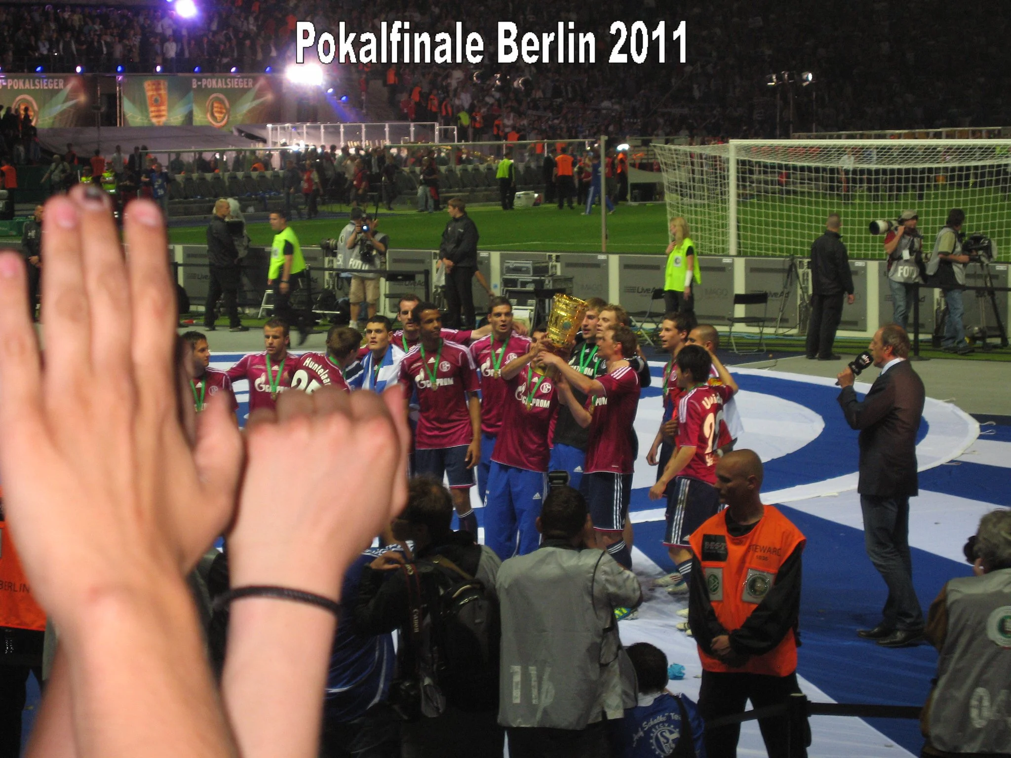 Fußballspieler feiern mit Pokal, während das Stadion gefüllt mit Zuschauern im Hintergrund ist. Es ist die Pokalfinales Berlin 2011.