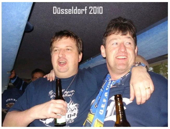 Zwei Männer auf einer Party in Düsseldorf 2010, die gemeinsam Bier trinken und die Arme um sich legen.