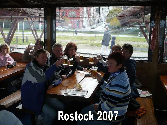 Eine Gruppe von acht Menschen sitzt in einer Biergartenhütte bei Rostock im Jahr 2007 und hebt ihre Bierkrüge zum Anstoßen.