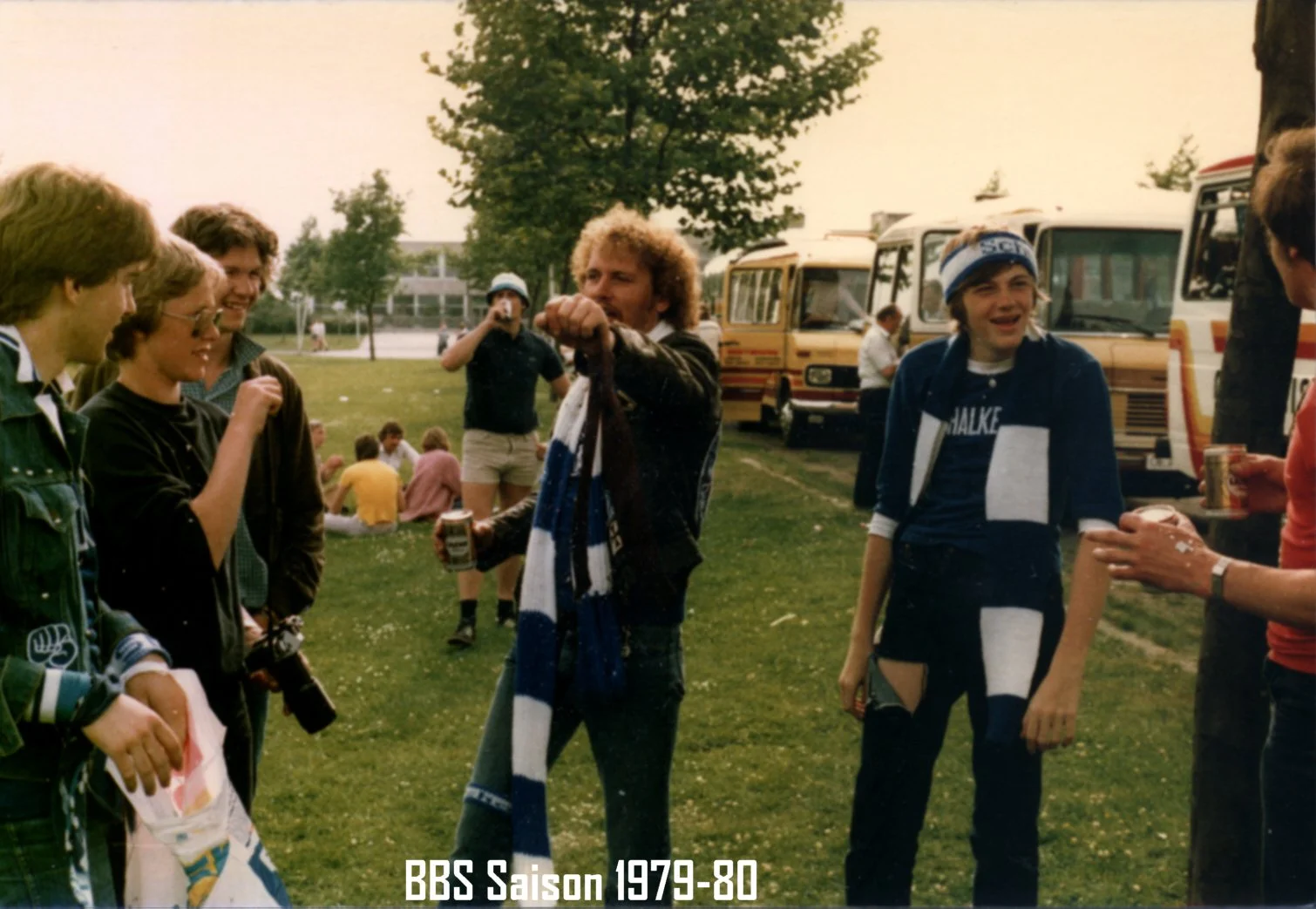 Gruppen von Menschen im Freien vor Bussen, mit einigen Personen in Fußballtrikots und -schals, im Jahr 1979-80. Titeltext: 'BBS Saison 1979-80'.