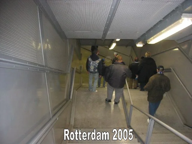 Menschen steigen eine Rolltreppe hinunter in einem Bahnhof, wahrscheinlich in Rotterdam im Jahr 2005.