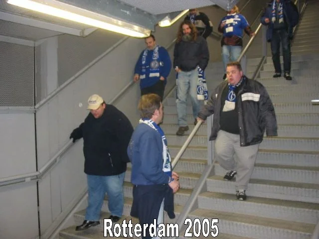 Menschen in 2000er-Jahren-Fußballtrikots und Schals, die die Treppe eines öffentlichen Ortes in Rotterdam 2005 hinuntergehen.