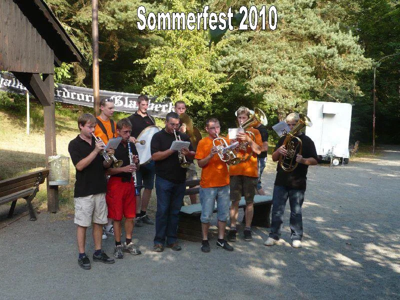 Gruppe junger Musiker spielt bei einem Sommerfest im Jahr 2010 draußen, mit Brass-Instrumenten wie Trompeten, Posaunen und einem Sousaphon.