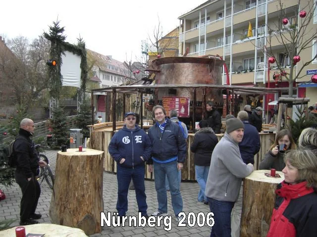Menschen vor einem Weihnachtsmarkt in Nürnberg im Jahr 2006, mit einer großen Sumpf- oder Kesselpfeife im Hintergrund, dekoriert mit Weihnachtsgirlanden und Weihnachtsbäumen.