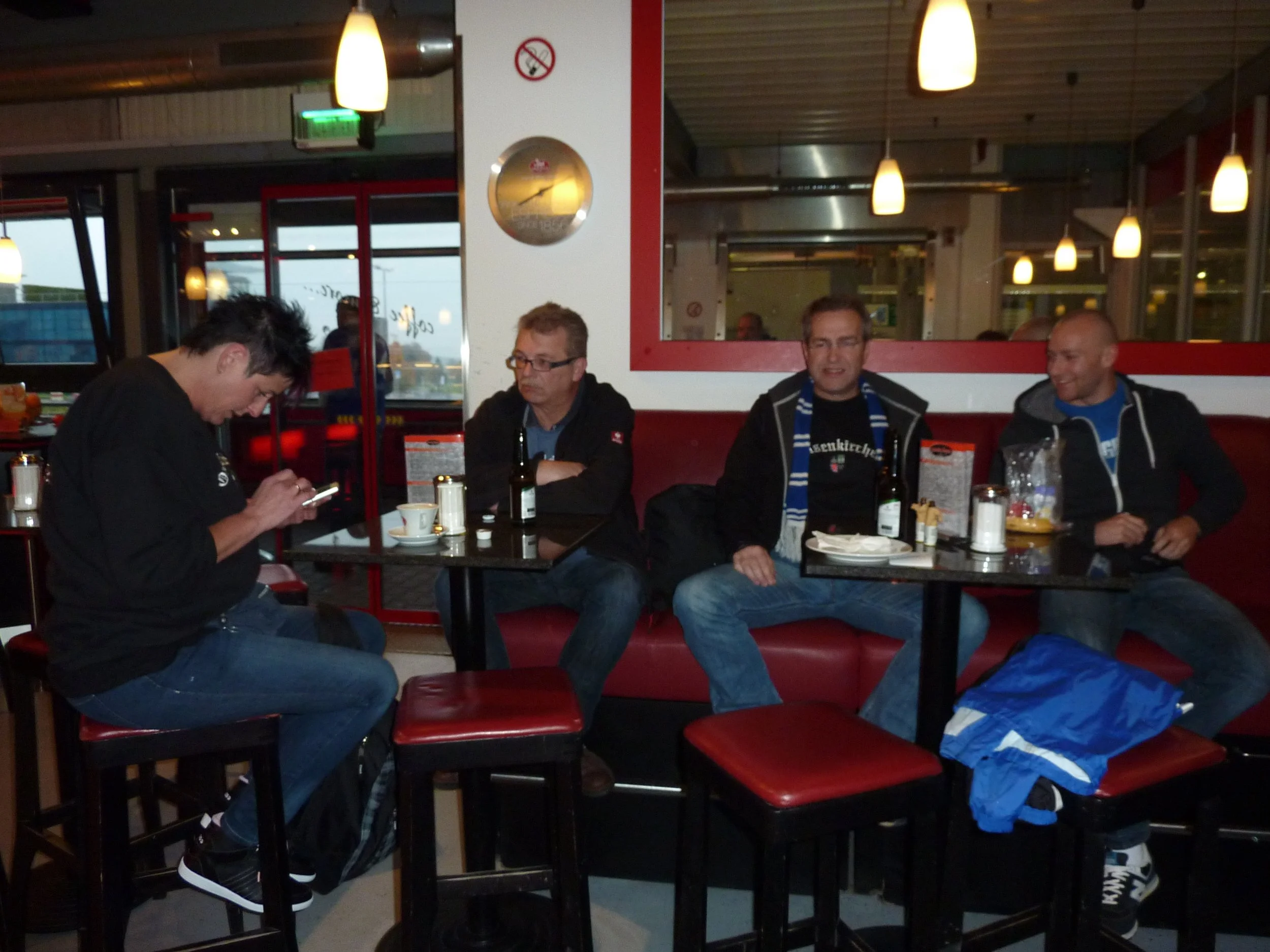 Menschen sitzen in einem Restaurant, trinken Bier und unterhalten sich. Es gibt einen Tisch mit Getränken, Essen und Geschirr.