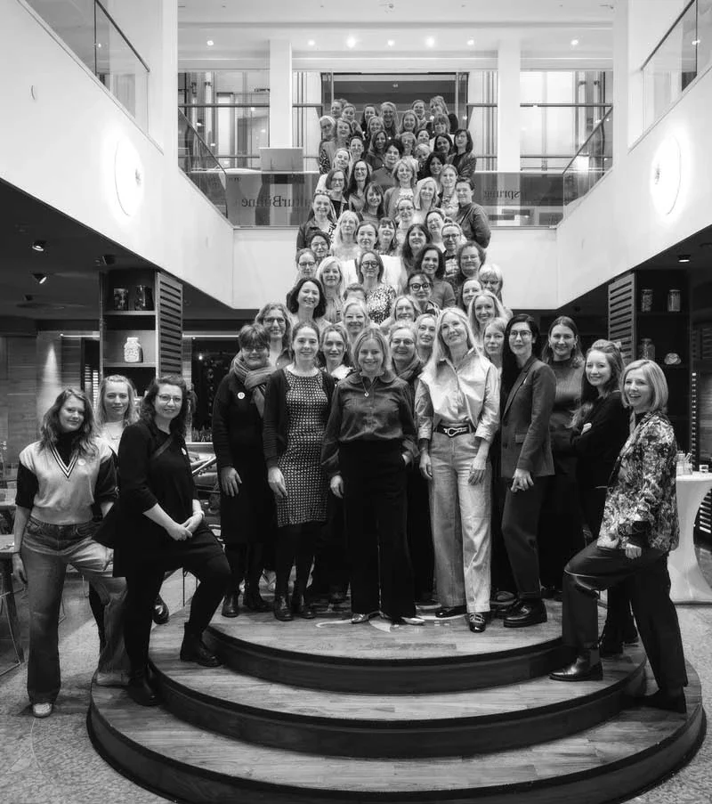 Gruppenfoto von vielen Menschen, die auf einer Treppe im modernen Innenraum stehen, zum Teil in Business- und Freizeitkleidung.