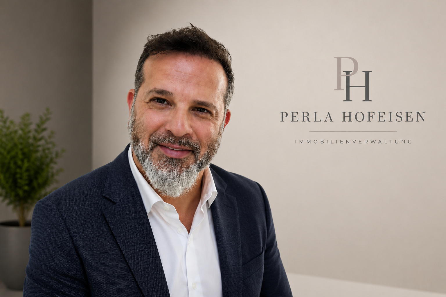 Ein Mann mit grauem Bart in Businesskleidung vor einer Wand mit dem Logo 'Perla Hofisen Immobilienverwaltung'.