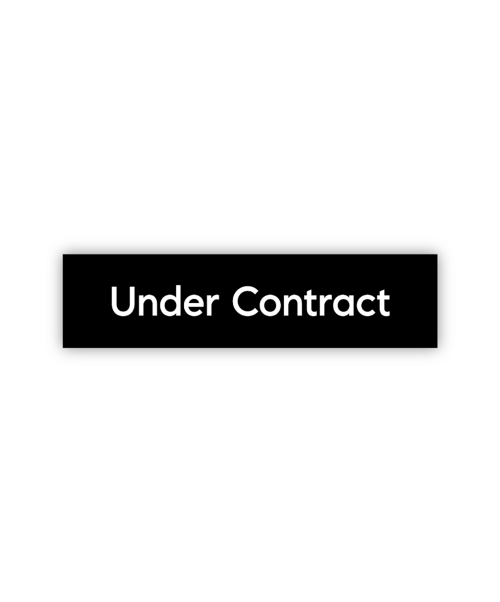 A designer's workspace with a card labeled "Under Contract" in the center, surrounded by papers, a pen, and a blurred phone on the desk.
