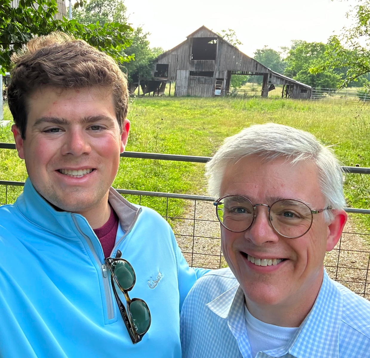 Two men taking a selfie outside in front of a barn