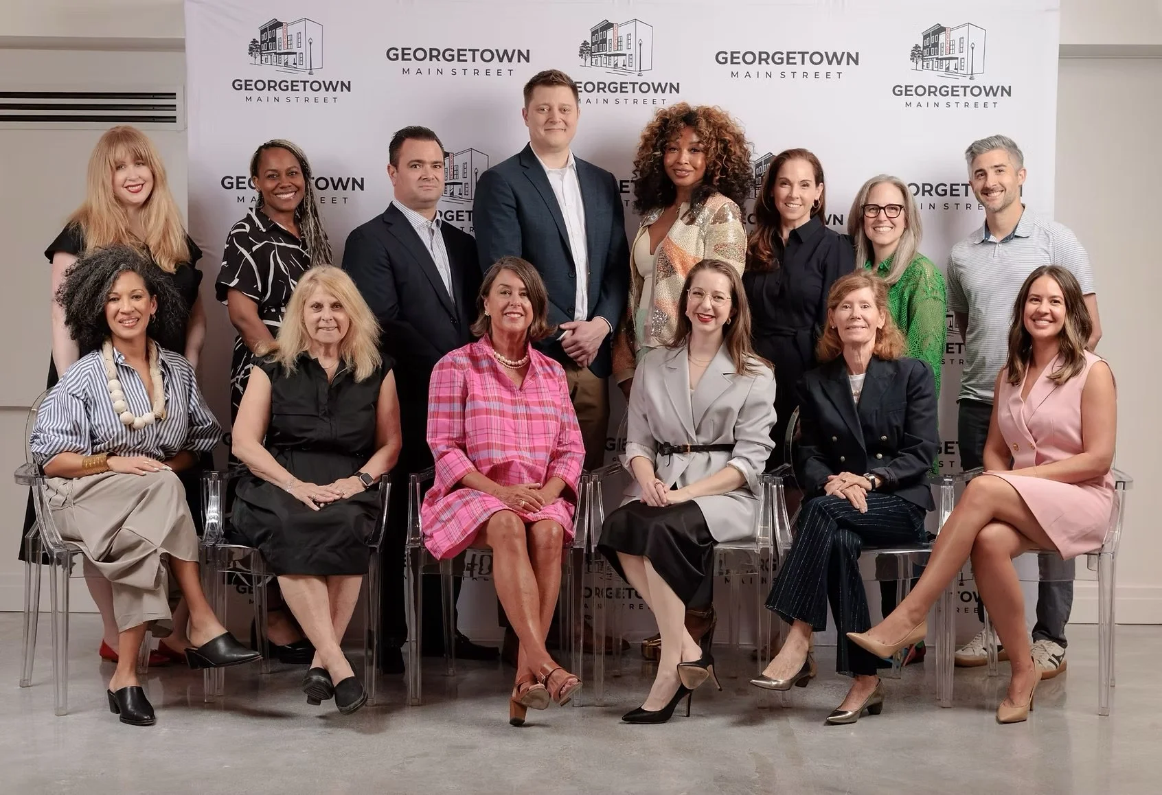 Group photo of diverse women and men dressed professionally, seated and standing in front of a backdrop with the Georgetown Main Street logo.