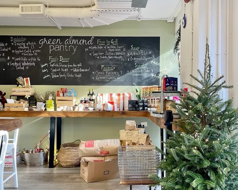Interior of a Green Almond Pantry with a blackboard menu on the wall, a wooden counter with various products.