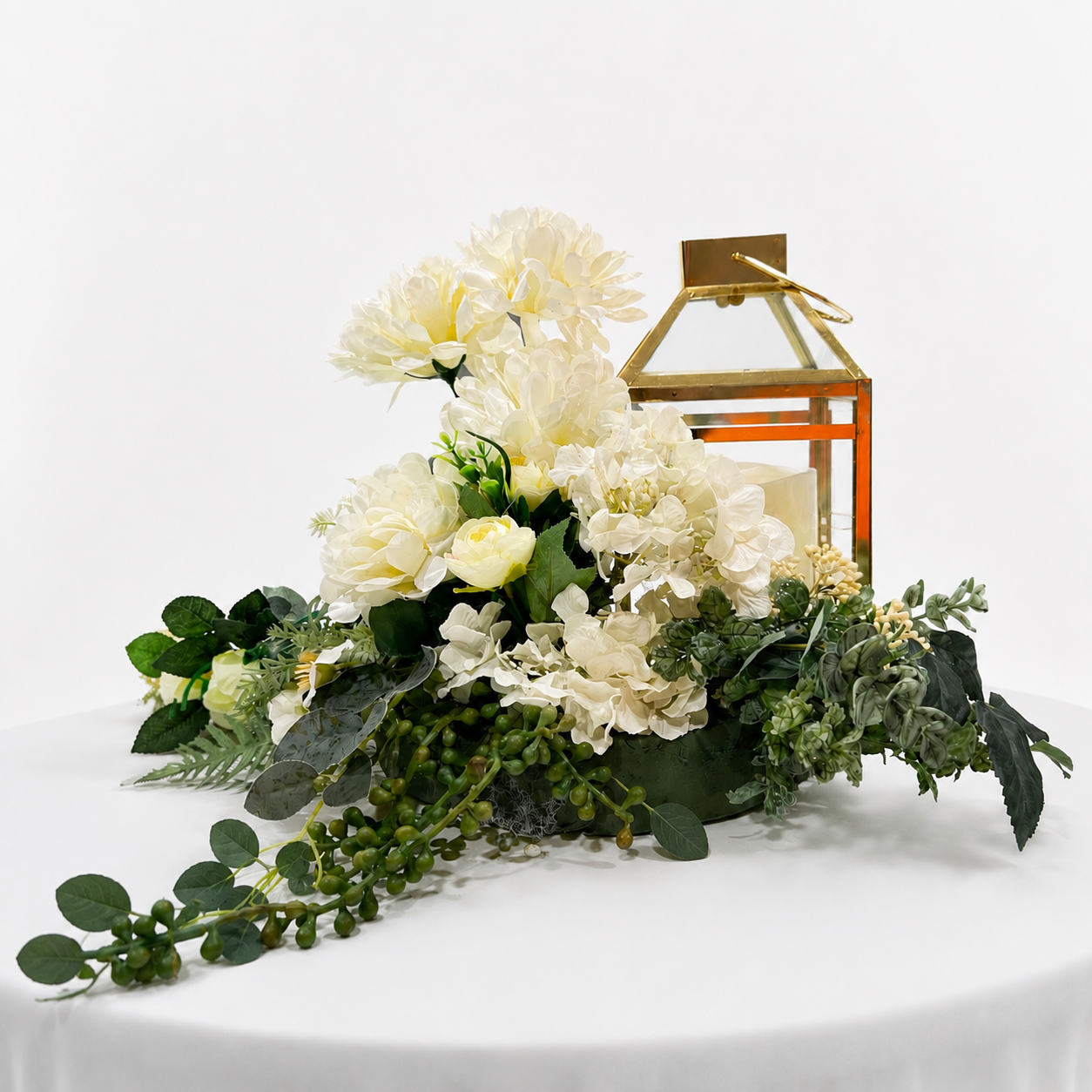 Table centrepiece white flower arrangement and gold lantern.