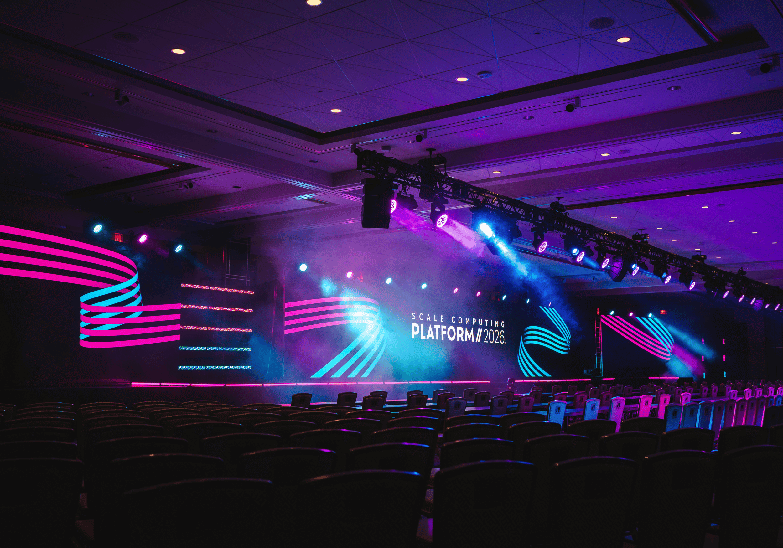 Exciting photo of Scale Computing Platform 2026 main stage with pink and blue lighting from the left side of the stage.