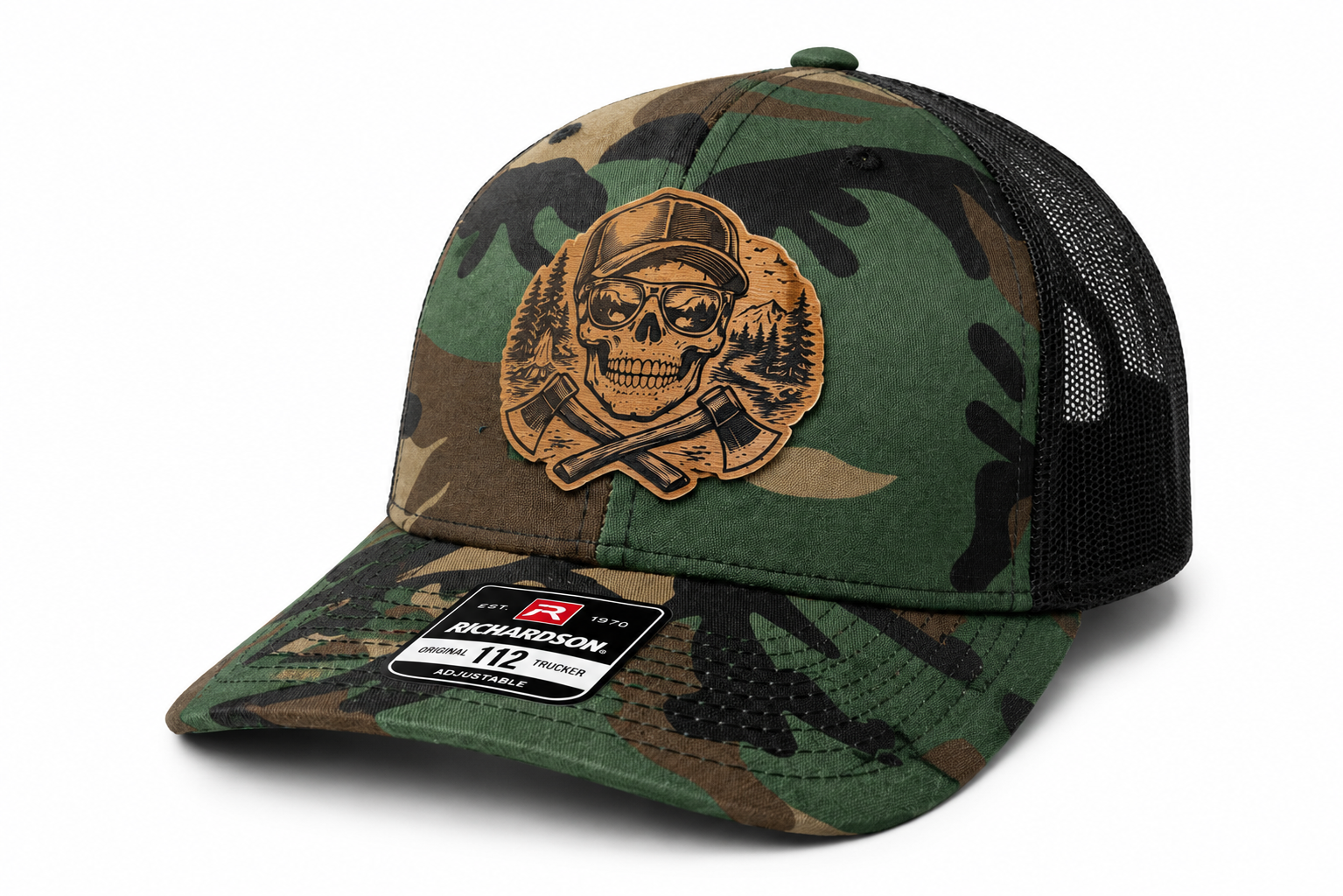 A camouflage trucker cap with a patch of a skull wearing a cap, surrounded by trees and mountains, and crossed axes on the front.
