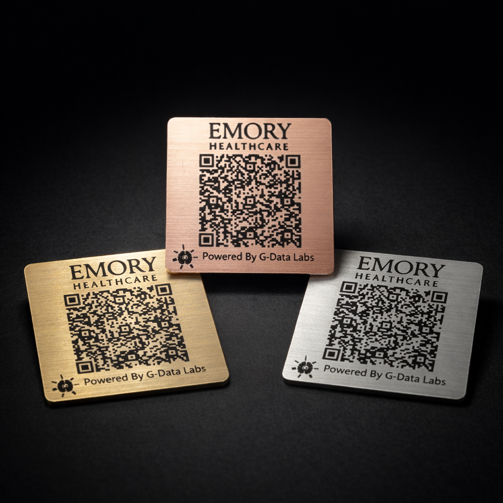 Three square metal cards with QR codes and 'Emory Healthcare' branding, in gold, pink, and silver colors, on a black background.