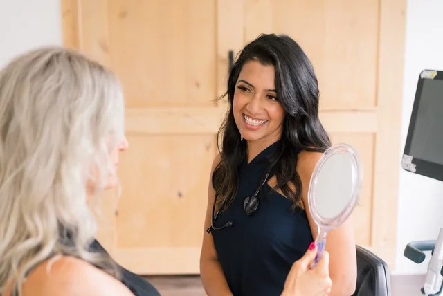 Female healthcare professional smiling and talking to a woman in a medical office.