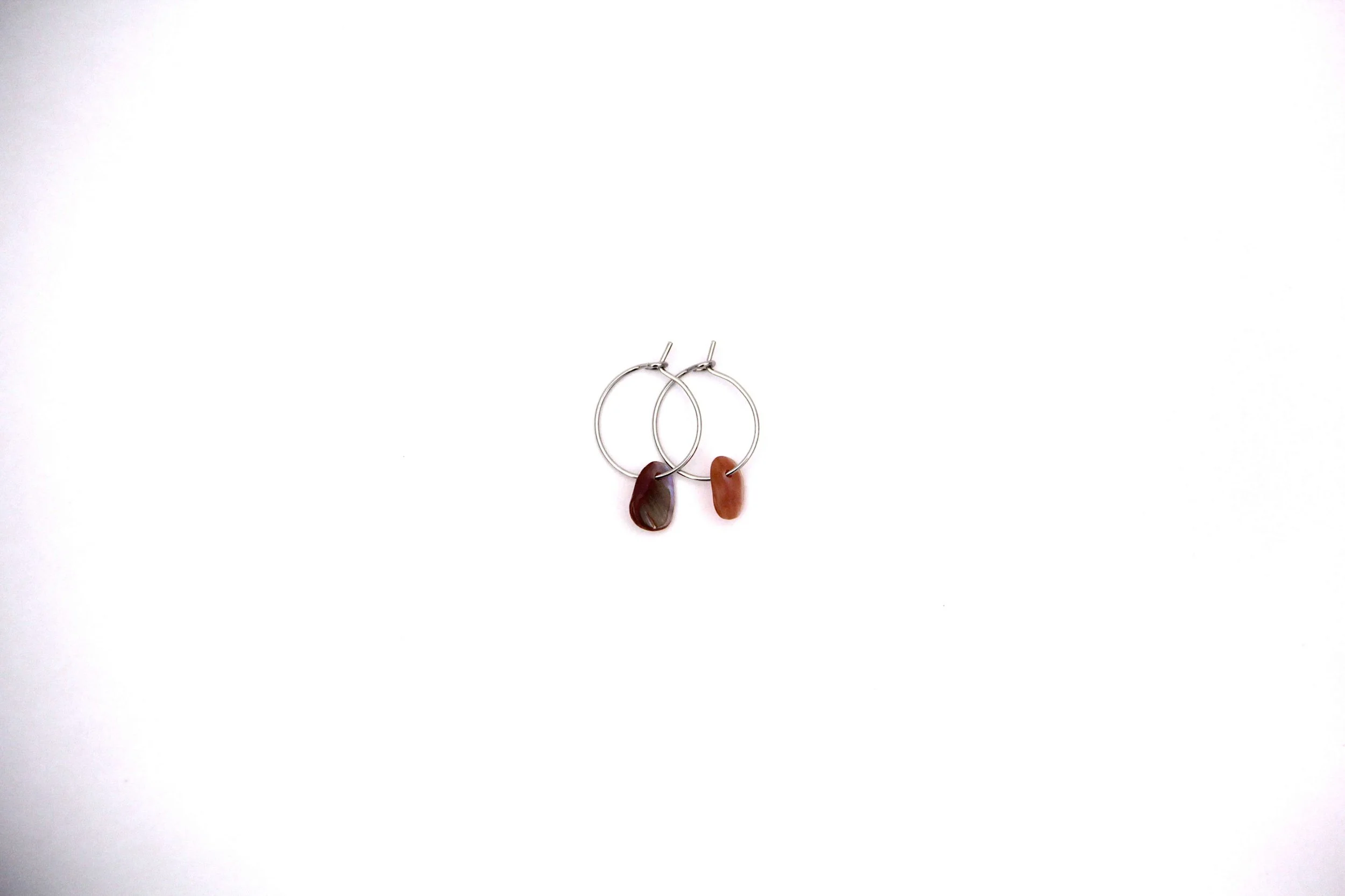 Silver stainless steel seashell hoop earrings on white background.
