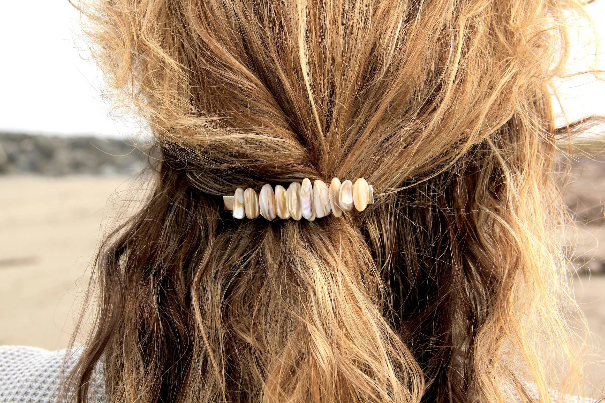 A close up of a woman wearing a genuine seashell silver hair clip in her hair.