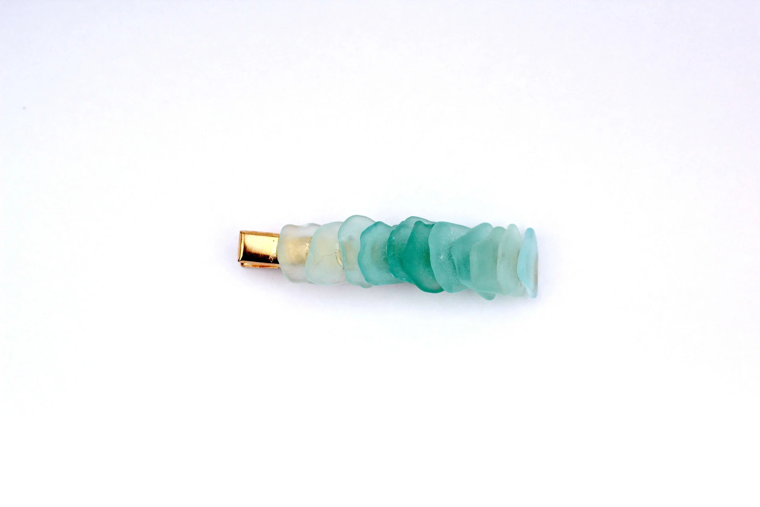 The front of a genuine ocean-tumbled sea glass gold hair clip on a white background.