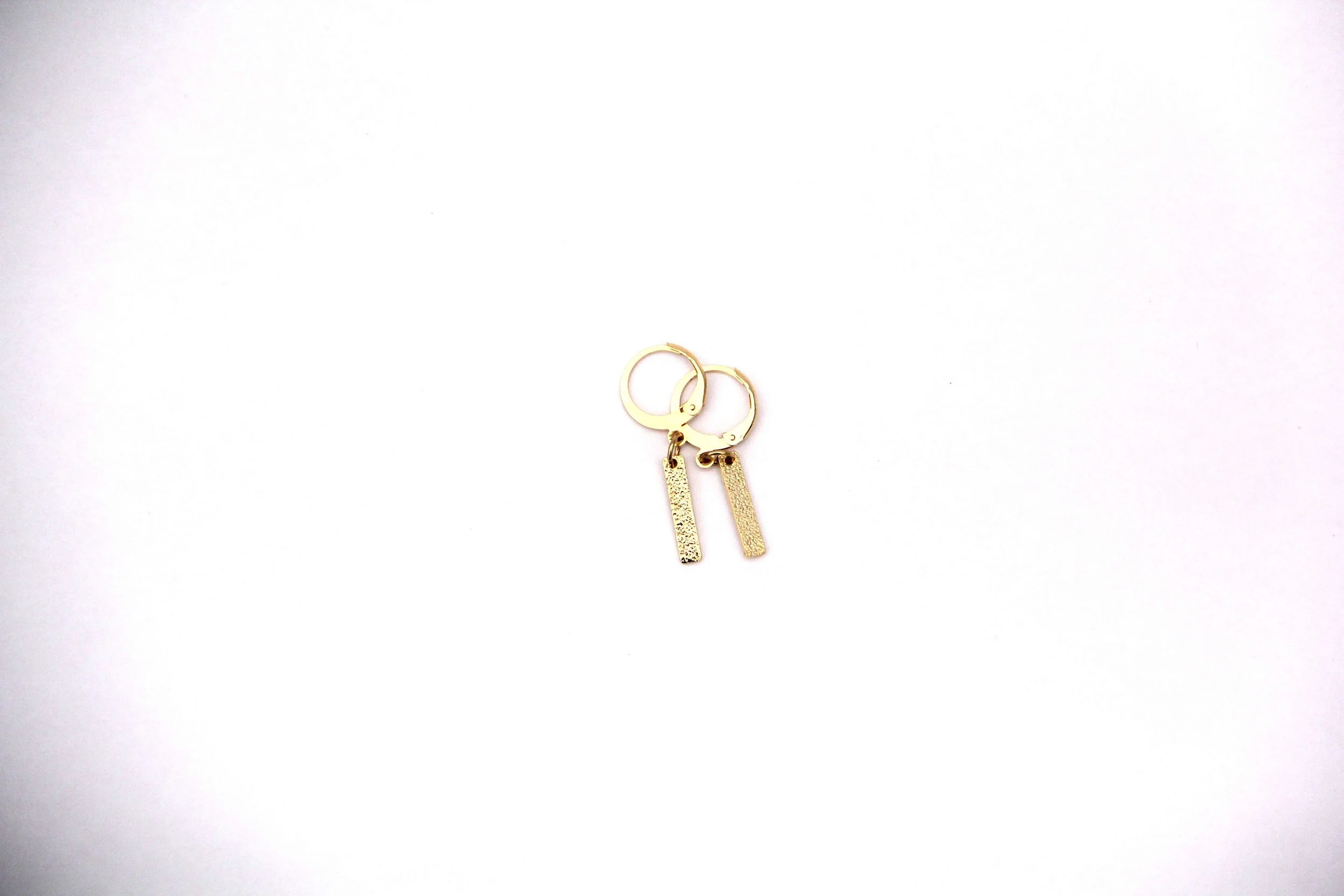 A pair of 18K gold-plated brass textured bar charm huggie hoop earrings on white background.