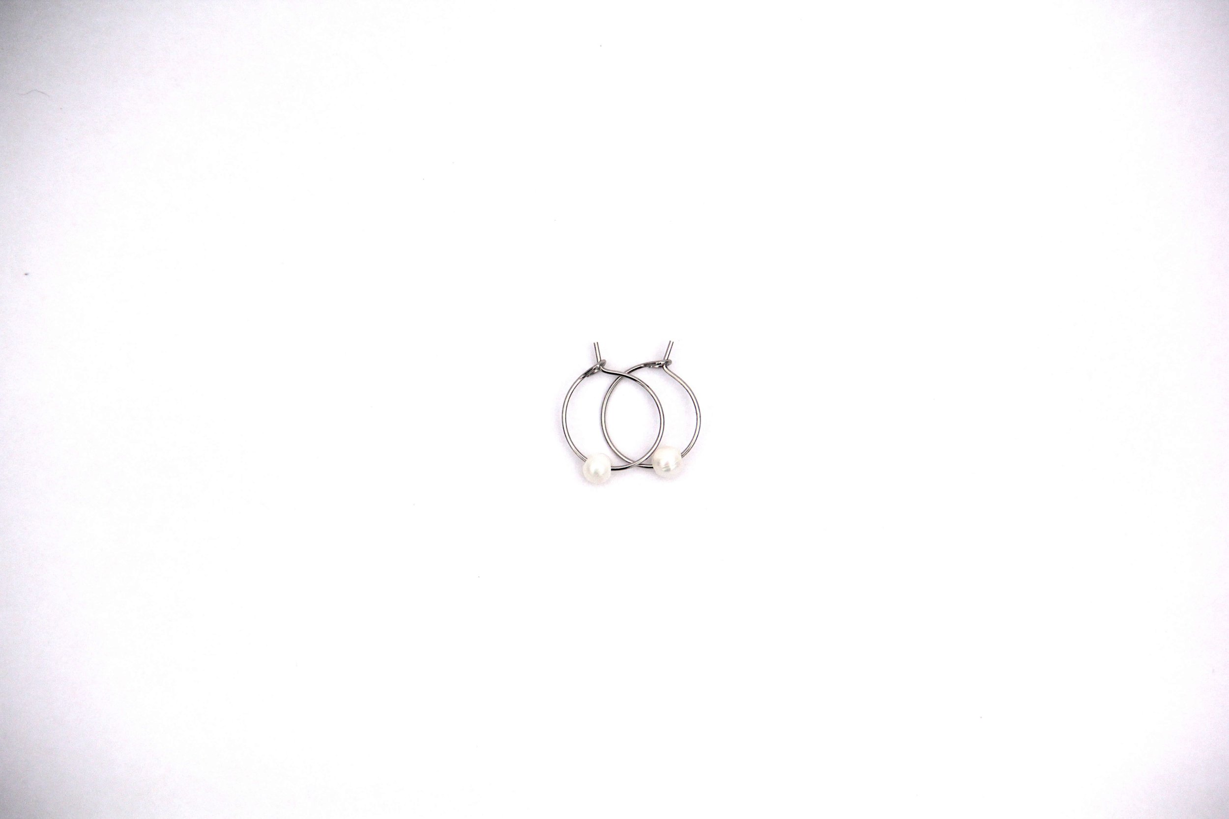 Silver stainless steel freshwater pearl hoop earrings on white background.