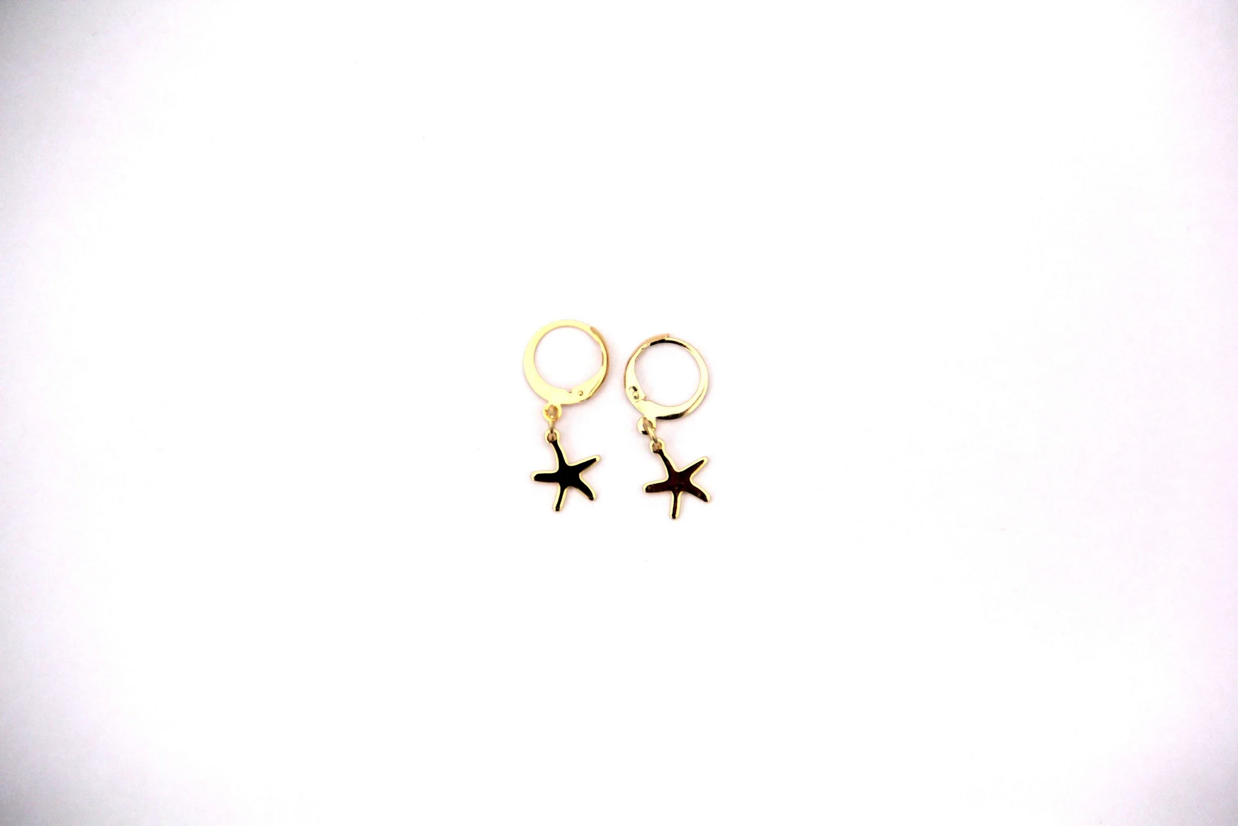 A pair of 18K gold-plated brass starfish charm huggie hoop earrings on white background.