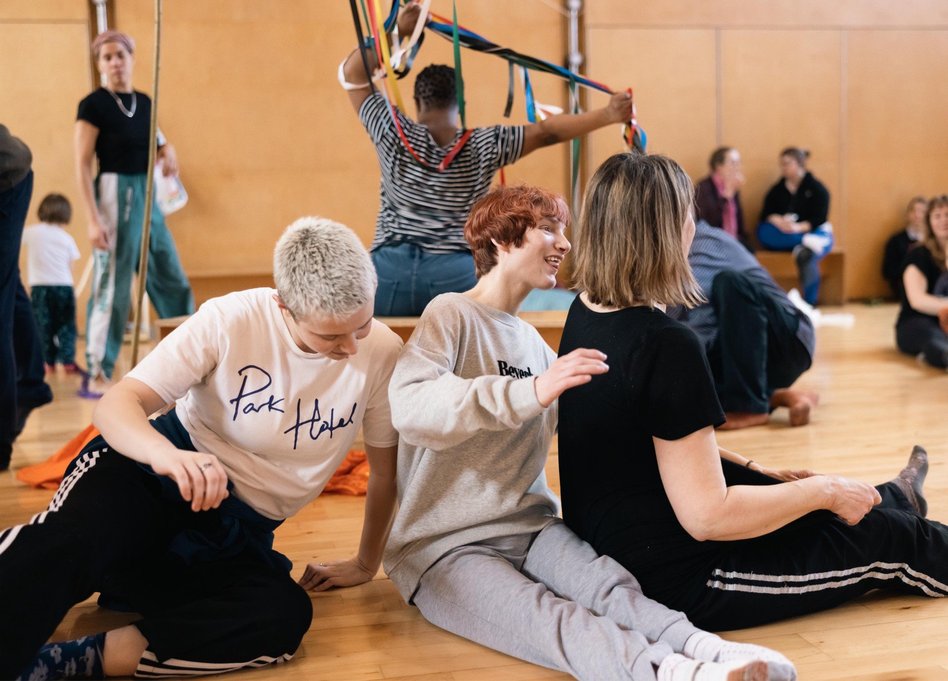 Three people sit in a line on the floor, dancing