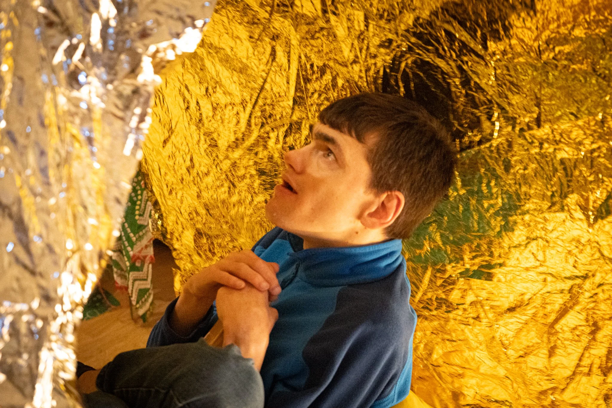 A man wearing a blue fleece sits beneath a tin foil canopy