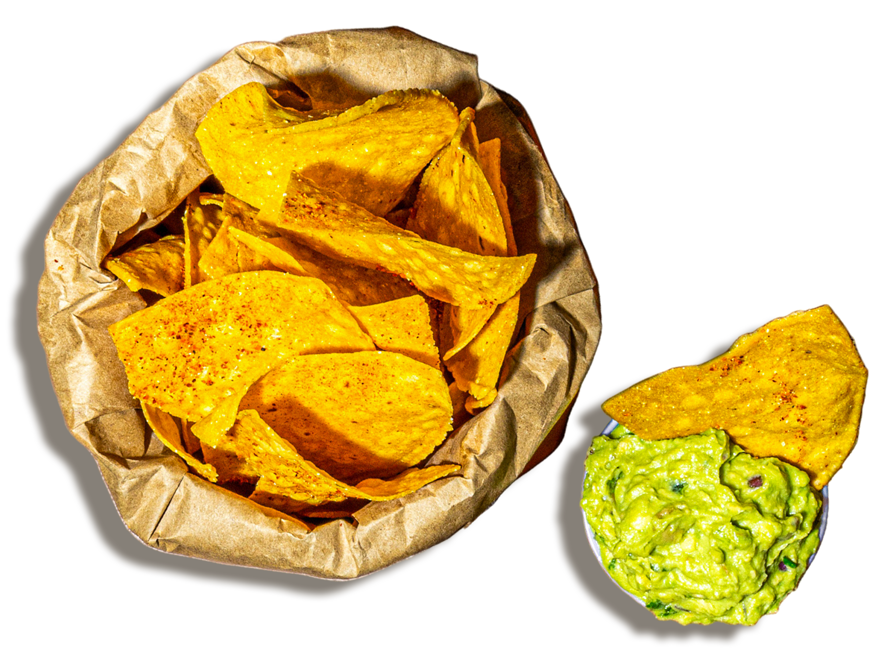 Yellow corn tortilla chips in a paper basket and a side of guacamole topped with a tortilla chip.